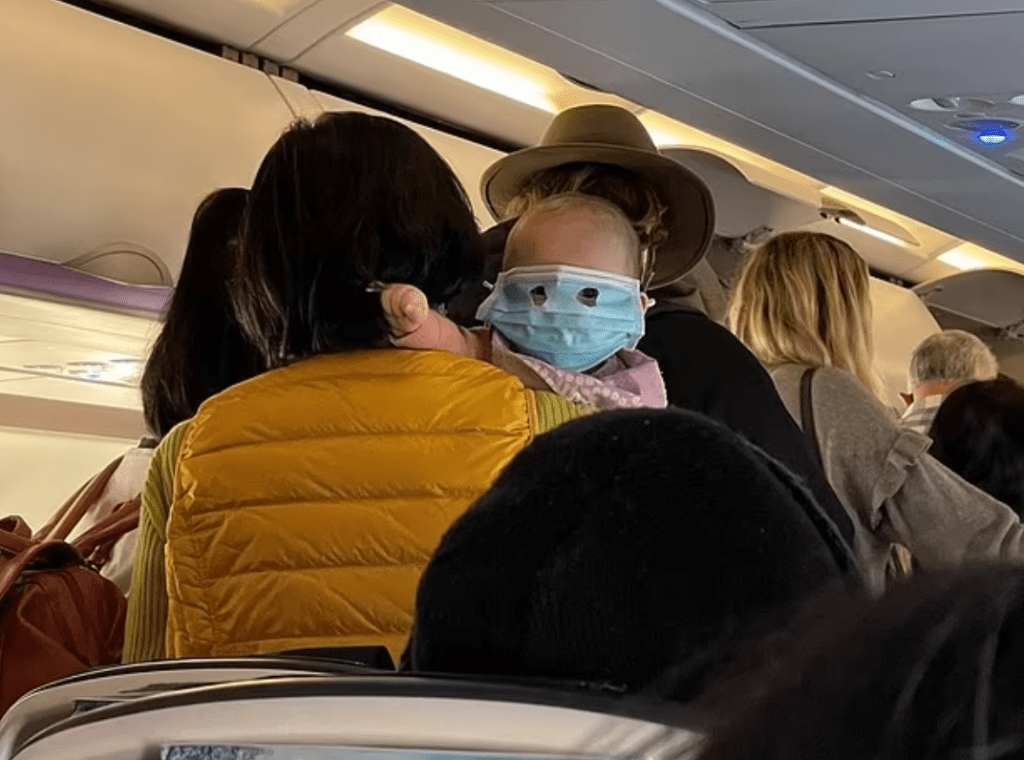 face-nappy:-baby-in-face-mask-on-plane-with-holes-cut-for-eyes-sparks-ridicule-and-anger
